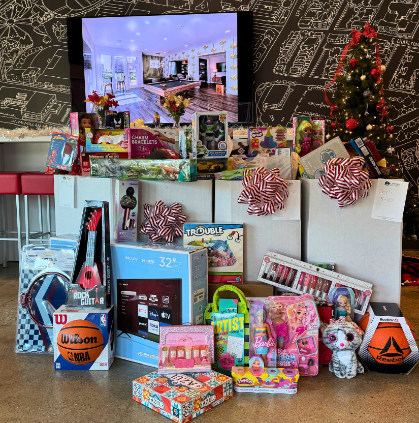 A collection of toys and boxes with bows in front of a Christmas tree at the 2024 Toy Drive.