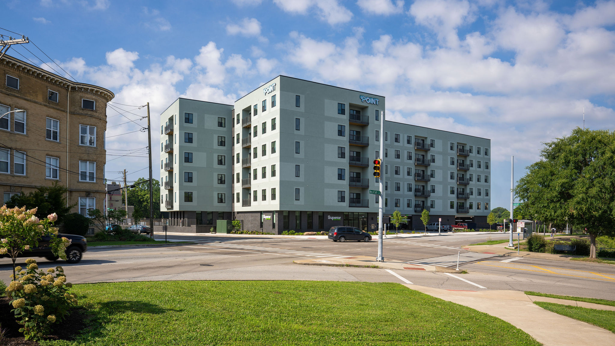 Exterior view of the Point apartment building with landscaped grounds next to a road with cars.